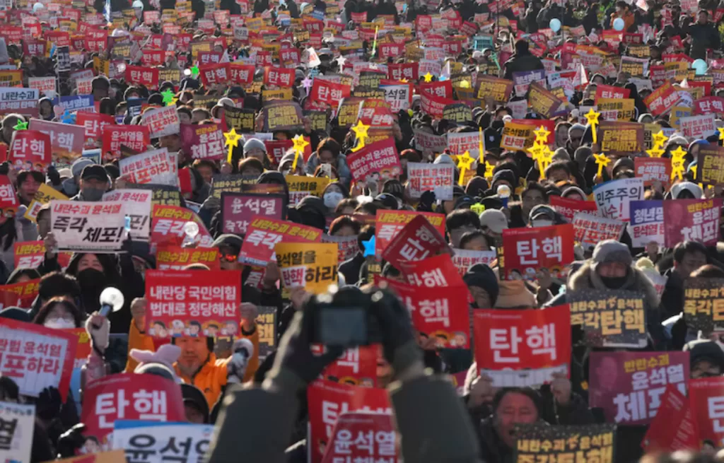 Una multitud corea eslóganes durante una manifestación para exigir la destitución del presidente de Corea del Sur, Yoon Suk Yeol, en el exterior de la Asamblea Nacional, en Seúl, Corea del Sur, el 14 de diciembre de 2024. Los carteles dicen "juicio político". (AP Foto/Lee Jin-man)